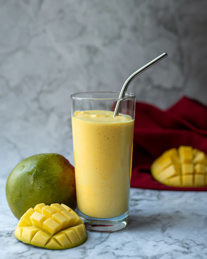 A mango smoothie next to a mango